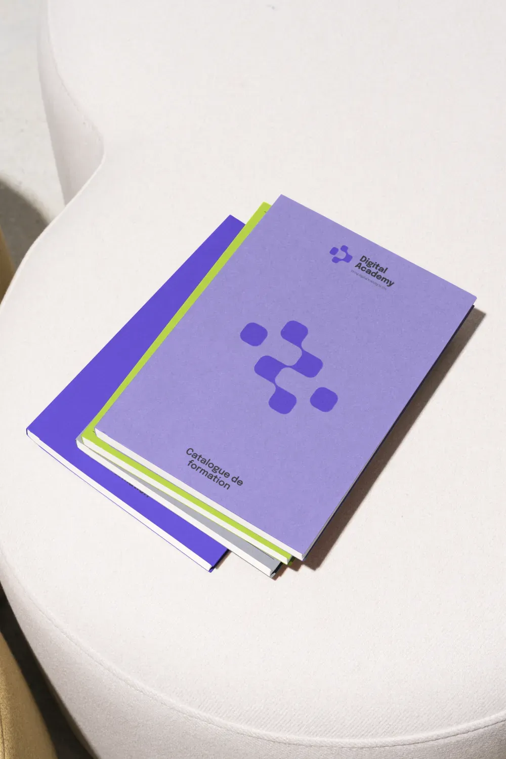 Catalogue de formation Digital Academy violet posé sur une table blanche, logo et motif géométrique en couverture