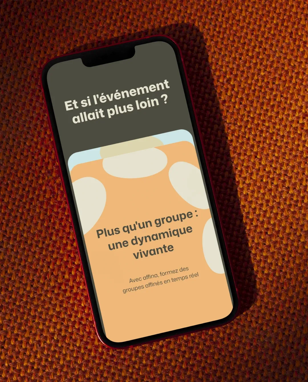 Smartphone affichant l'écran Affina « Plus qu'un groupe : une dynamique vivante » sur un tissu orange