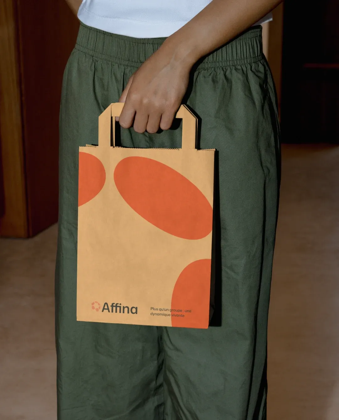 Sac kraft Affina orné de formes orange, porté à la main